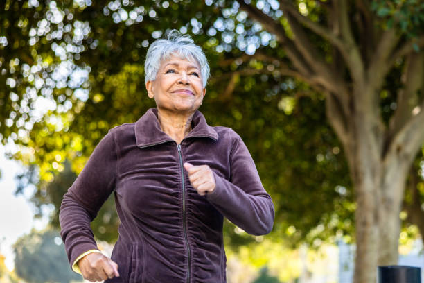 Senior woman running on a beautiful day outdoors under trees