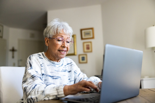 Mujer mayor que usa una computadora portátil en casa photo