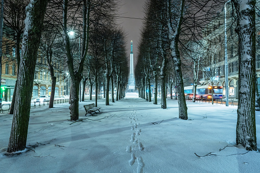 Alley at night in a snowfall. The Freedom Monument can be seen in the distance