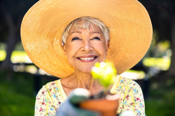 una mujer de raza mixta haciendo jardinería en el patio - planting clothing gray hair human age fotografías e imágenes de stock