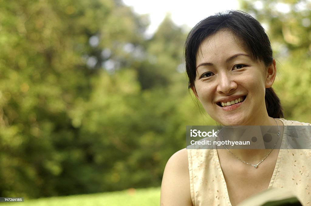 Chinese lady in garden A young chinese asian lady looking at camera and smile at garden. Adult Stock Photo