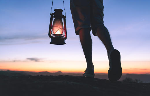 Walking at night while carrying a kerosene lamp. Walking and taking steps in the right direction.