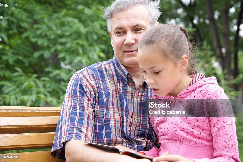 Father and daughter reading Father and daughter reading a book in park 10-11 Years Stock Photo