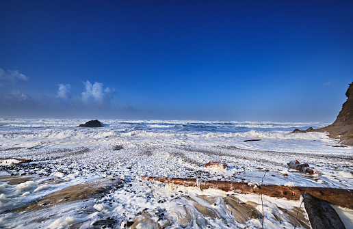 Winter high tide tosses huge logs around on the beach at Arch Cape, Oregon
