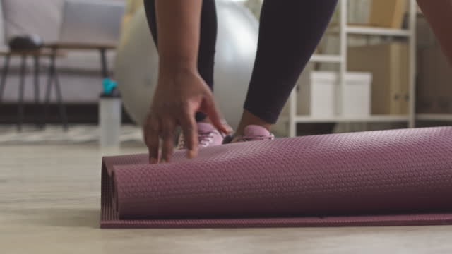 Black Woman Rolling up Mat after Sports Training Low Section