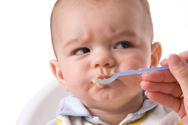 Eating little boy is looking very angry Eating little boy is looking very angry and annoyed baby spoon stock pictures, royalty-free photos & images