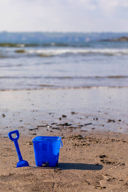 istock A blue bucket and spade with waves in the background 1472653090