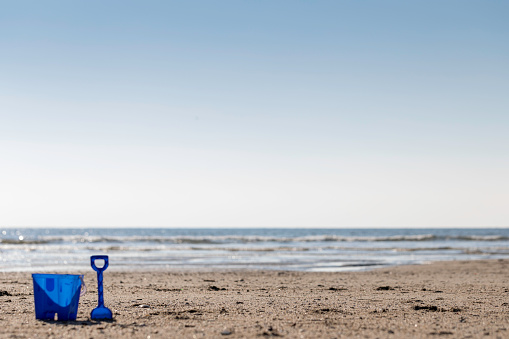 A blue kids bucket an spade by the sea