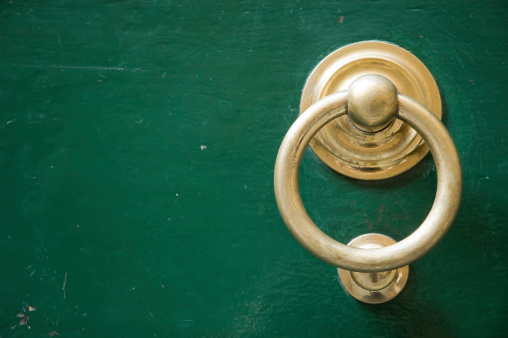 Old elegant golden metal door handle, knocker. Photo taken in Tuscany Italy