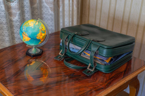 Spain. Old room. Outdated objects. Sixties suitcase next to illuminated world globe in retro style. Vintage curtains and old table. Concept: Journeys of the past
