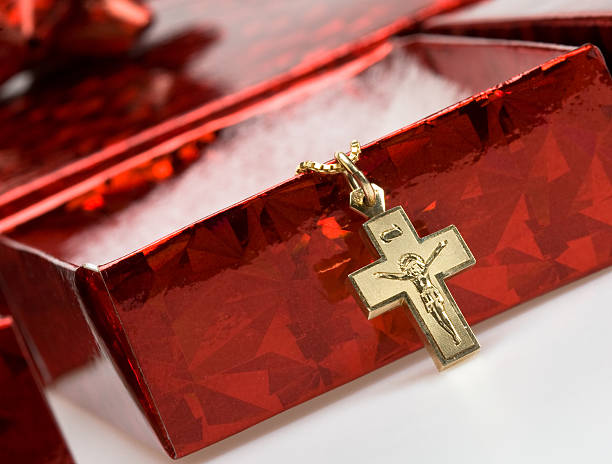 Red box with gold chain and cross draped over stock photo