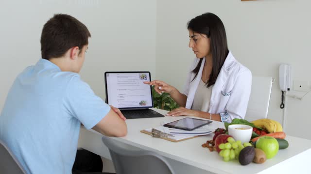 Nutricionist doctor and deportologist during a medical consultation with teenager boy patient