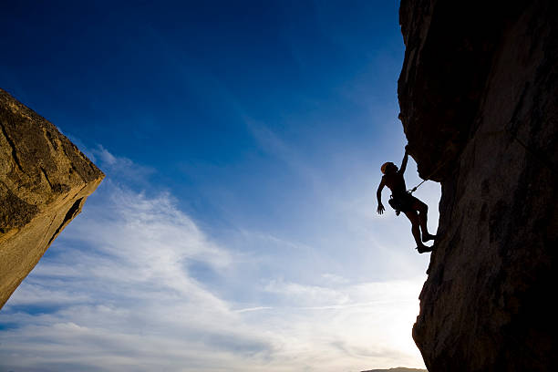 istock Rock climber clinging to a cliff as he climbs higher 147266059