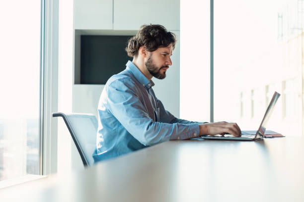 istock Business man using laptop sitting at desk in modern office 1472661376
