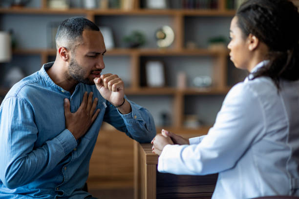 istock Sick black patient coughing while having checkup with doctor 1472661516