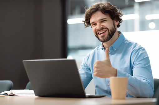 I Like. Portrait Of Happy Excited Middle Aged Business Man Sitting At Desk Using Laptop And Showing Thumbs Up Sign Gesture, Working At Office Or Studying Remotely, Posing To Camera, Selective Focus
