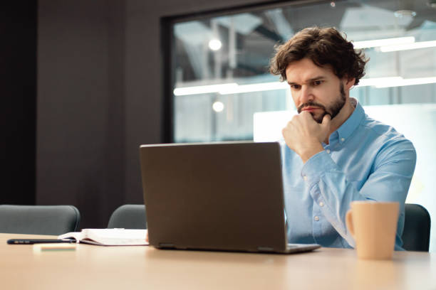 istock Focused man using laptop sitting at desk in office 1472661535