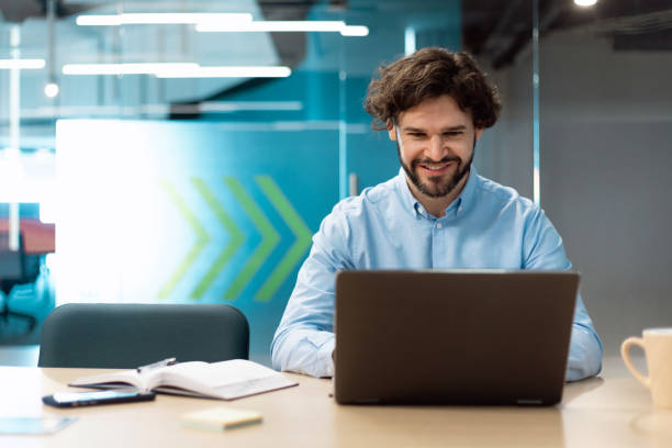 istock Smiling businessman using laptop sitting at desk in office 1472661542