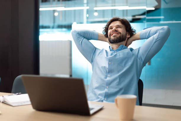 istock Taking break. Smiling middle aged man relaxing on chair, sitting at table and resting, using pc laptop at office 1472661571