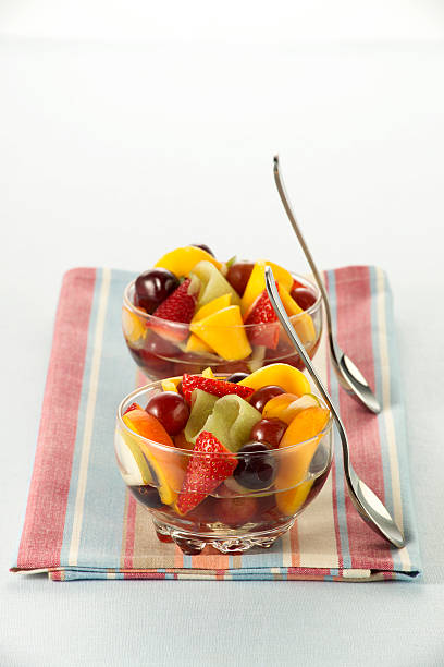 Glass bowls of fruit salad with upright spoons stock photo