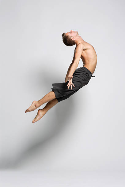 Portrait of a male dancer jumping gracefully modern ballet dancer posing over white background jazz dancing stock pictures, royalty-free photos & images