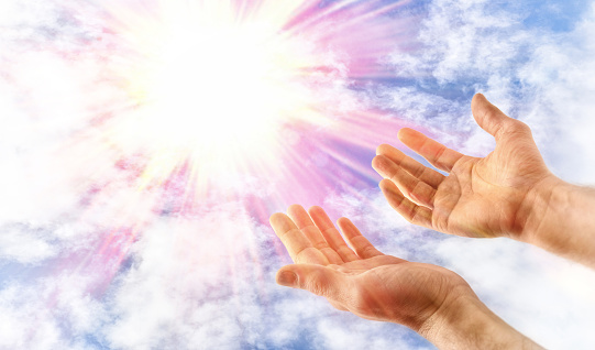 Hands outstretched to heaven in a religious gesture of offering to God with spiritual sparkle