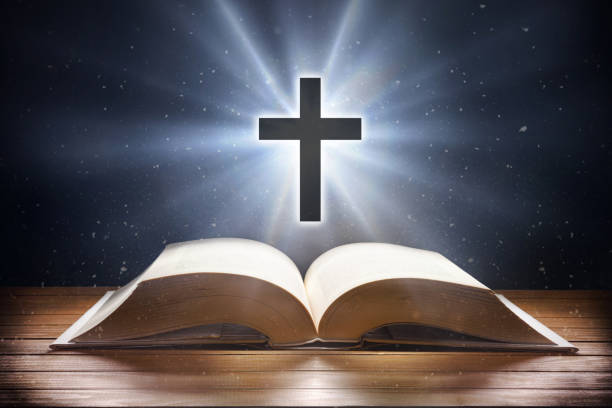 istock Bible on table and cross with flare and universal background 1472669560