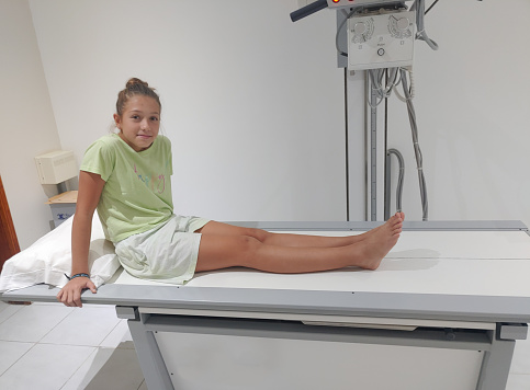 Little blond girl on the table in an x-ray room waiting to have a radiograph