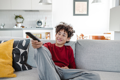 Shot of cute boy feeling comfortable while watching TV at home