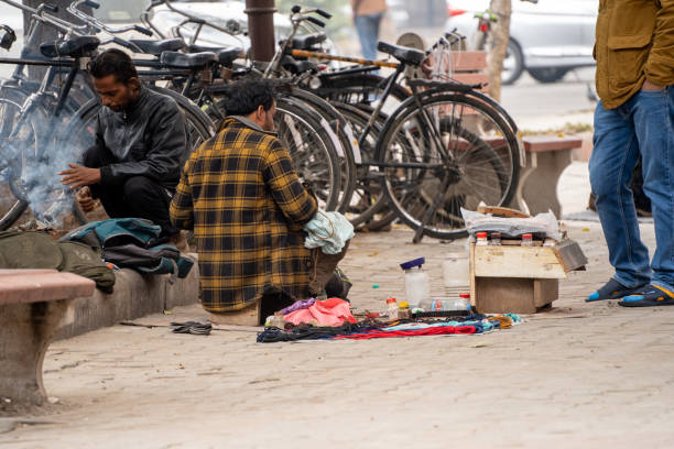 street side cobbler sitting on road and mending shoes in the winter months in sector 17 chandigarh during morning showing how the poor earn a living stock photo