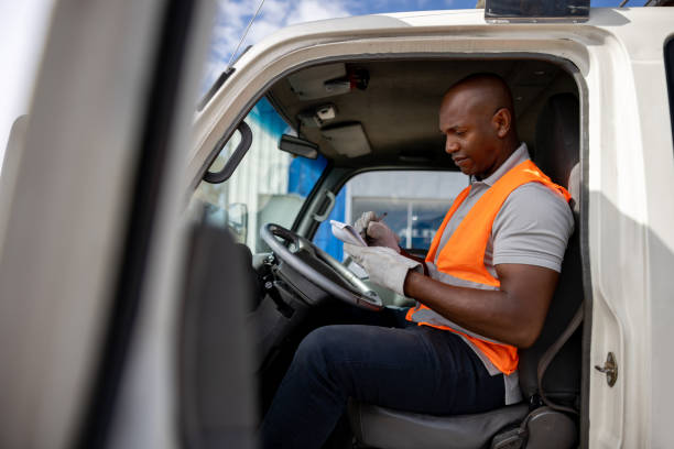 istock Truck driver sitting in his vehicle an taking notes on a notepad 1472673459