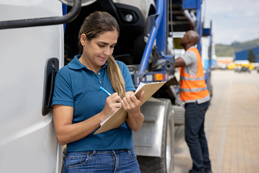 Latin American woman working at a distribution warehouse supervising the transportation of cars