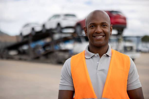 istock Man working at a distribution warehouse and loading vehicles on a car transporter 1472673472