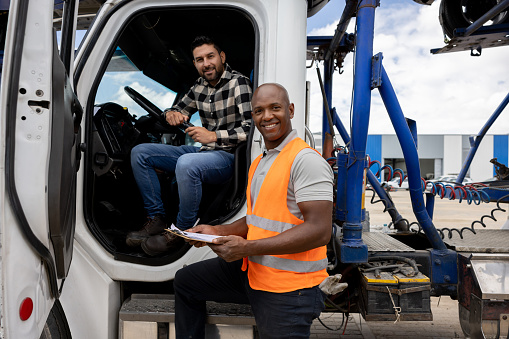 Truck driver and his supervisor working on the freight transportation business and looking at the camera smiling