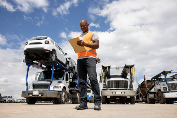 man working at a distribution warehouse supervising the shipment of cars - full length clipboard african ethnicity black imagens e fotografias de stock