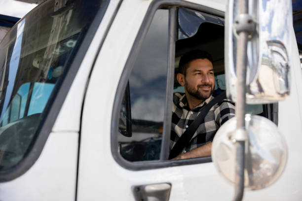 Happy truck driver driving his cargo vehicle Happy truck driver driving his cargo vehicle and smiling - freight transportation concepts truck driver stock pictures, royalty-free photos & images