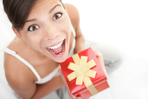 Happy excited woman holding gift / present. Cute surprised mixed Asian Chinese / Caucasian female model. Click for more: