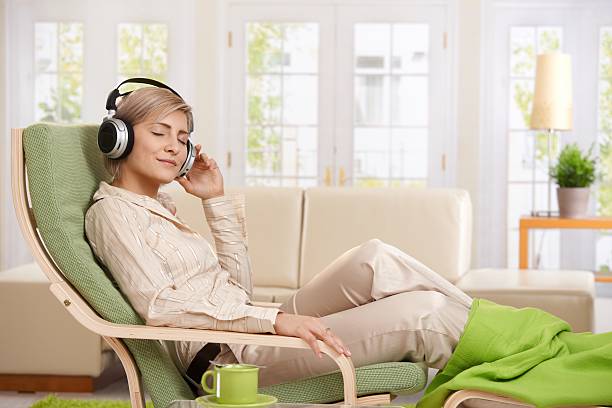 女性が家庭でくつろいでいる - armchair comfortable relaxation headphones ストックフォトと画像