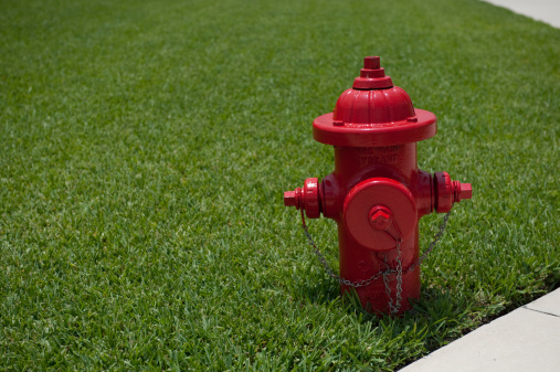 Iconic red fire hydrant against green grass and sidewalk