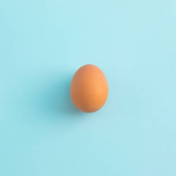 istock Uncooked egg on pastel blue background. Minimal food concept with copy space. Top view, flat lay. 1472681137
