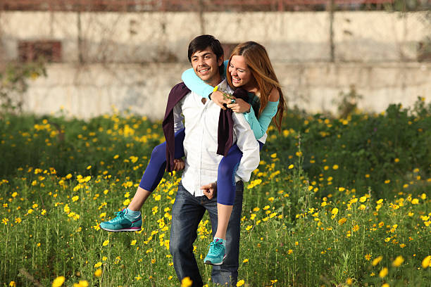 Young couple piggy-backing in meadow stock photo