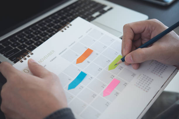 istock 2023 Calendar event planning timetable agenda plan on organize schedule. Event planner agenda organizing by organizer schedule. Business man hand note on notebook with calendar planner on office table 1472692395
