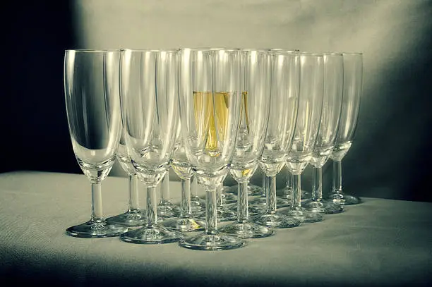 Halffull champagneglass surrounded by empty glasses