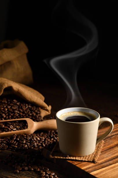tazza di caffè con fumo e chicchi di caffè su vecchio sfondo di legno - coffee bag coffee bean bean foto e immagini stock