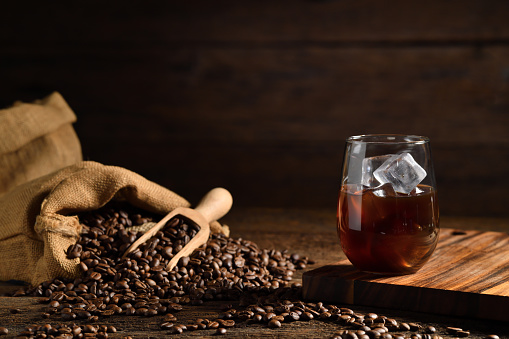 Glass of ice coffee  and coffee beans on old wooden background