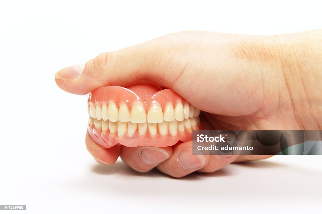 A hand holding a complete set of dentures The total denture upper and lower held in the hand Bridge - Built Structure Stock Photo