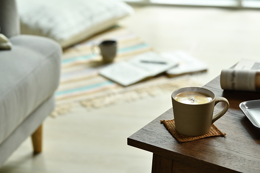 Cup of coffee with smoke on a table in living room at home