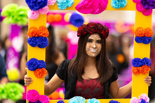 Matamoros, Tamaulipas, Mexico - November 1, 2022: Dia de los Muertos Parade, young women carry frames with flowers, dress up as catrinas