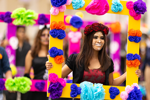 Matamoros, Tamaulipas, Mexico - November 1, 2022: Dia de los Muertos Parade, young women carry frames with flowers, dress up as catrinas