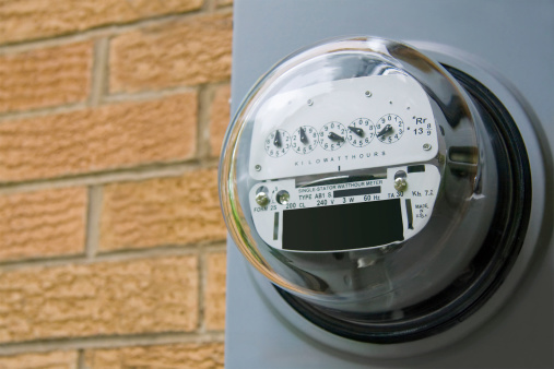 An electric meter on the side of a residential structure.